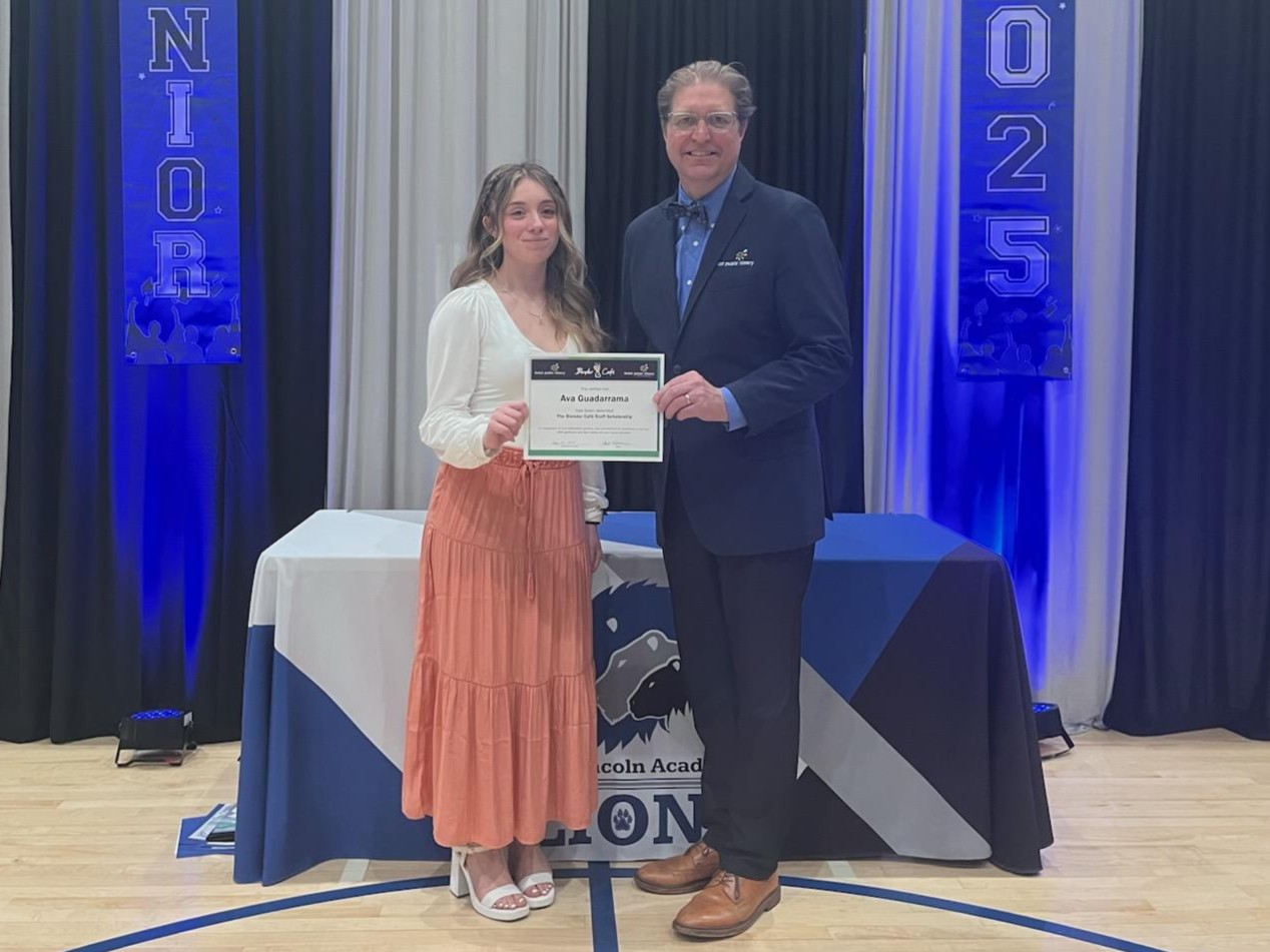 Young woman in skirt and blouse standing next to a man in a suitcoat and bowtie holding a certificate in front of them